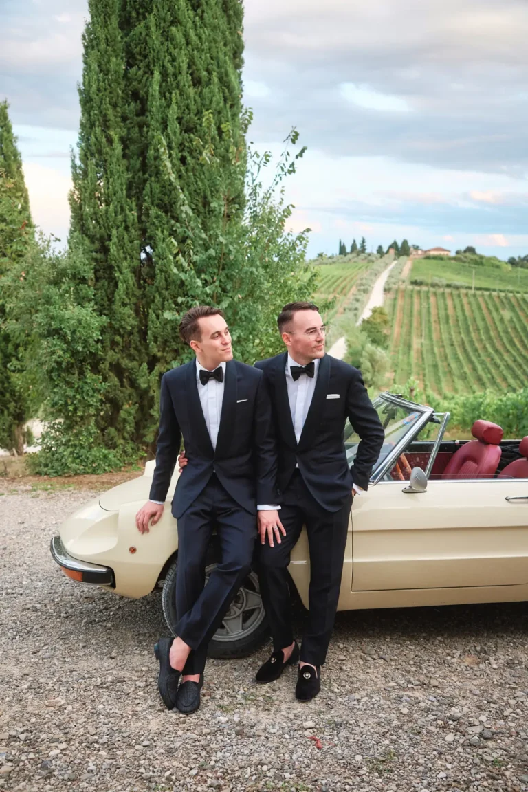 the extraordinaire lgtbq plus wedding planner in italy stylish couple poses by vintage car