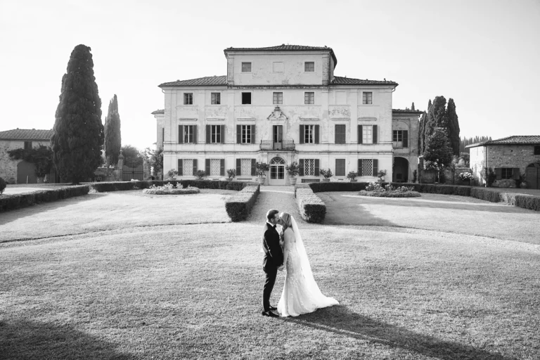 the extraordinaire tuscany villa di geggiano black and white romantic photo of couple kissing in front of villa
